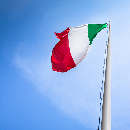 National flag of Italy on a flagpole in front of blue sky
