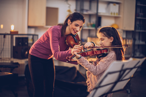 Two people, woman violin teacher working with little boy on violin lessons.