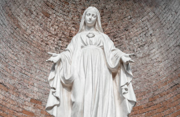 Statue in stone of Virgin Mary Statue in stone of Virgin Mary. On background, red brick wall. Ideal for christmas and easter concepts and other. virgin mary stock pictures, royalty-free photos & images