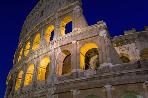 Part of ancient amphitheater Coliseum illuminated at night, Rome, Italy.