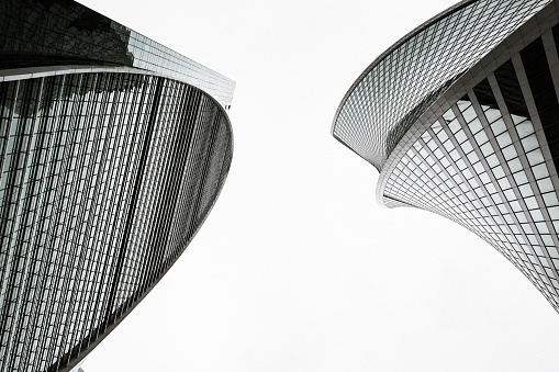 Skyscrapers with glass facades. Abstract modern buildings exterior, vintage stylized with grain. Bottom up view. Black and white.