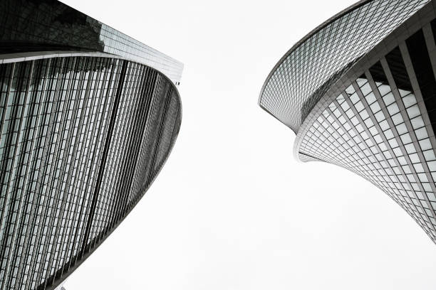 Top of two skyscrapers. Skyscrapers with glass facades. Abstract modern buildings exterior, vintage stylized with grain. Bottom up view. Black and white. black and white architecture stock pictures, royalty-free photos & images