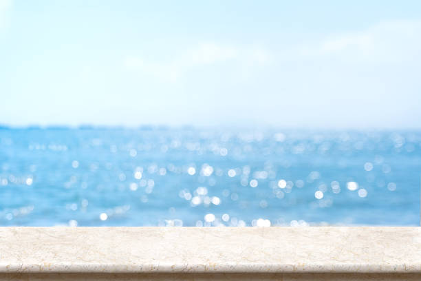 istock White marble table top with blurred bokeh sea and blue sky at background, Mock up template for display or montage of your product, Summer vacation concept,panorama view.. 1130670390
