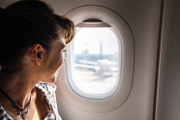 istock Happy woman enjoying while looking through plane window. 1130671655