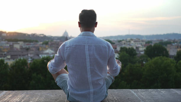 istock Man meditating in lotus pose. Looking at cityscape during sunset 1130673680
