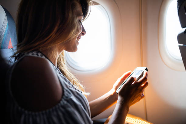 istock Happy woman text messaging on cell phone in a plane. 1130673689