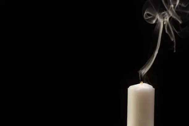 Photo of Candle with extinguished flame in front of black background