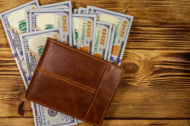 istock Brown leather wallet and american dollars on wooden table. Top view 1130678902