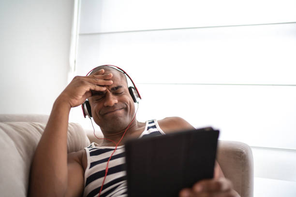istock Afro man using digital tablet at home sitting on the sofa 1130681571