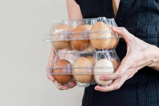 istock Caucasian woman with black shirt holding two plastic egg boxes full of chicken eggs 1130681821