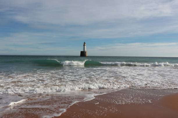 istock Seascape with white lighthouse on stone platform in sea 1130683180