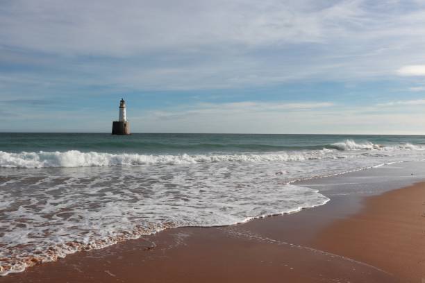 istock Seascape with white lighthouse on stone platform in sea 1130683182
