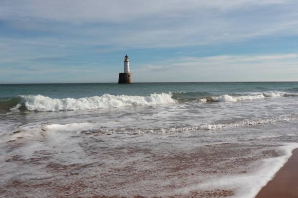 istock Seascape with white lighthouse on stone platform in sea 1130683184