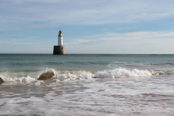 istock Seascape with white lighthouse on stone platform in sea 1130683187