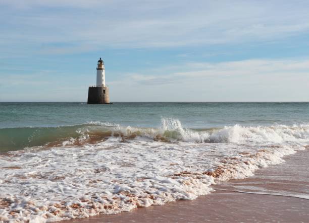 istock Seascape with white lighthouse on stone platform in sea 1130683195