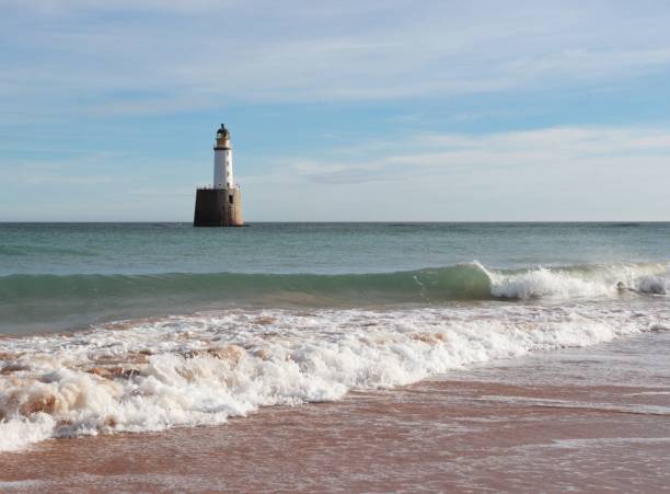 istock Seascape with white lighthouse on stone platform in sea 1130683196