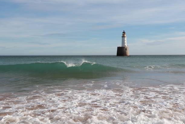 istock Seascape with white lighthouse on stone platform in sea 1130683199
