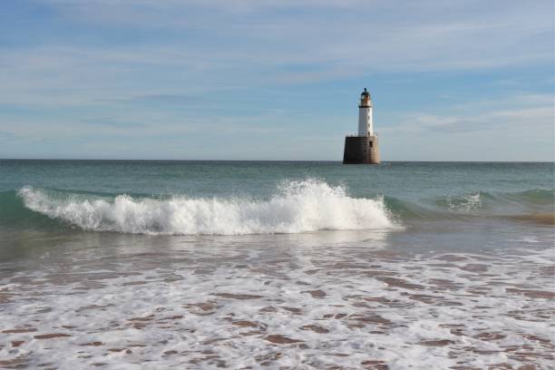 istock Seascape with white lighthouse on stone platform in sea 1130683205