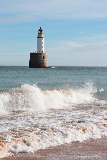 istock Seascape with white lighthouse on stone platform in sea 1130683217