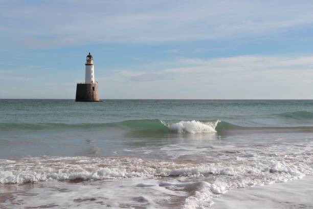 istock Seascape with white lighthouse on stone platform in sea 1130683219