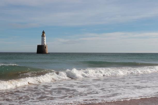 istock Seascape with white lighthouse on stone platform in sea 1130683222