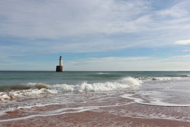 istock Seascape with white lighthouse on stone platform in sea 1130683228