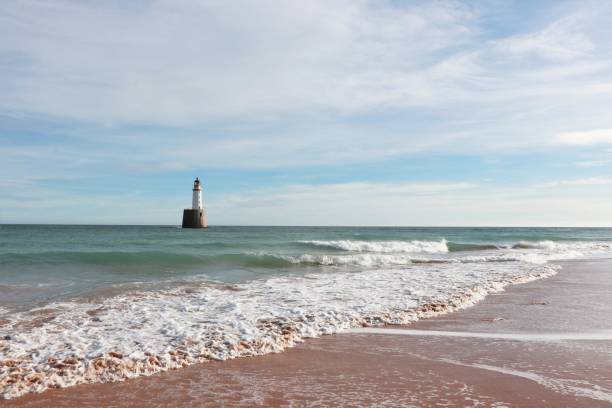istock Seascape with white lighthouse on stone platform in sea 1130683230