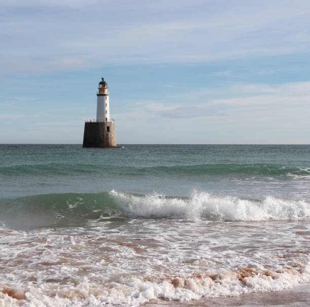 istock Seascape with white lighthouse on stone platform in sea 1130683231