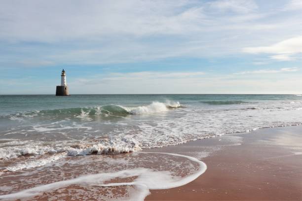 Seascape with white lighthouse on stone platform in sea