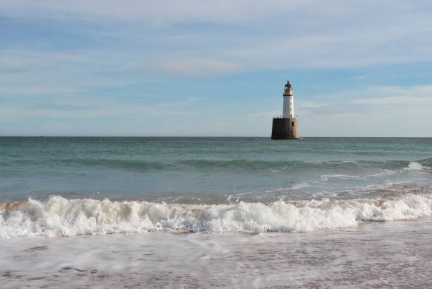 istock Seascape with white lighthouse on stone platform in sea 1130683257