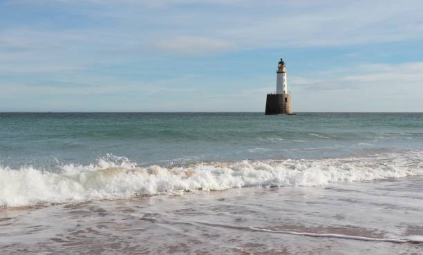 istock Seascape with white lighthouse on stone platform in sea 1130683264