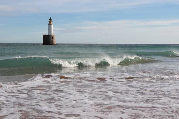 istock Seascape with white lighthouse on stone platform in sea 1130683279
