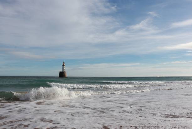 istock Seascape with white lighthouse on stone platform in sea 1130683281