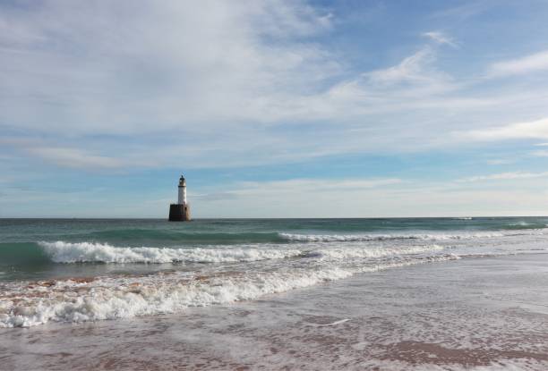 istock Seascape with white lighthouse on stone platform in sea 1130683285