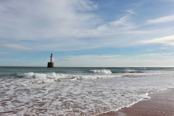 istock Seascape with white lighthouse on stone platform in sea 1130683290