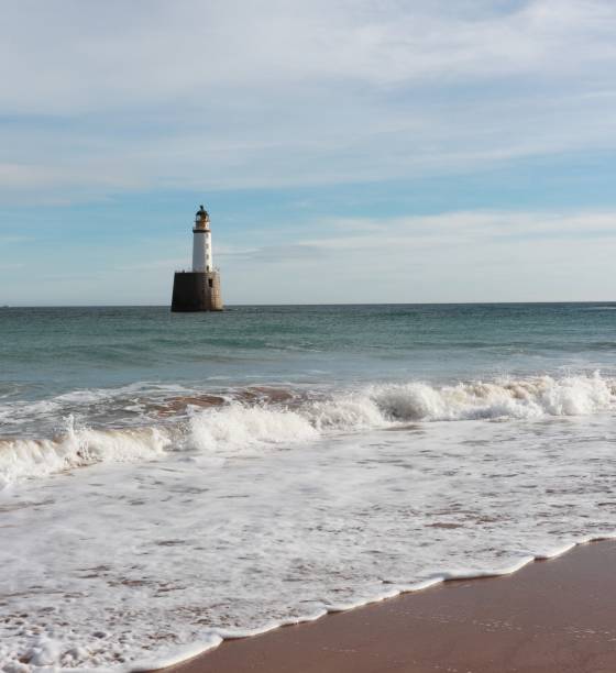 istock Seascape with white lighthouse on stone platform in sea 1130683294
