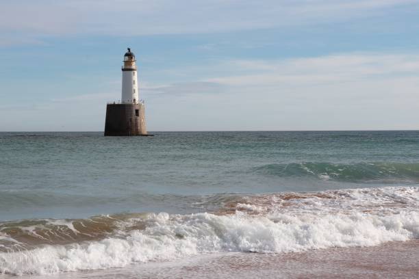 istock Seascape with white lighthouse on stone platform in sea 1130683299