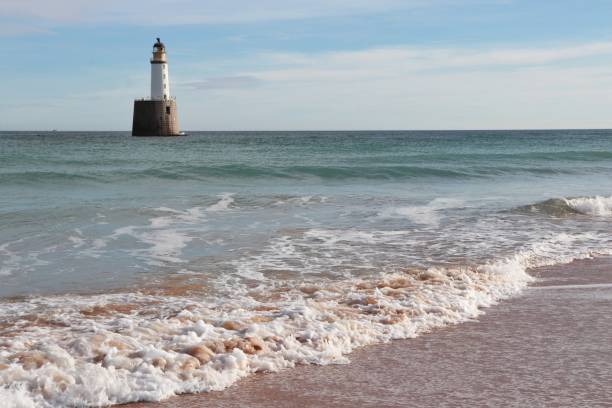 istock Seascape with white lighthouse on stone platform in sea 1130683309