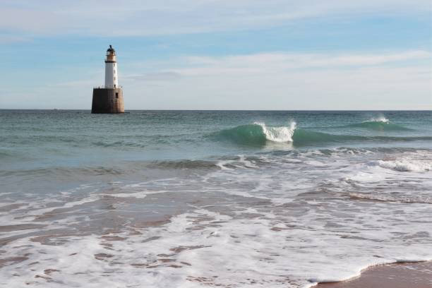 istock Seascape with white lighthouse on stone platform in sea 1130683312