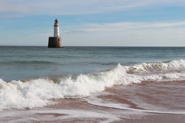 istock Seascape with white lighthouse on stone platform in sea 1130683313