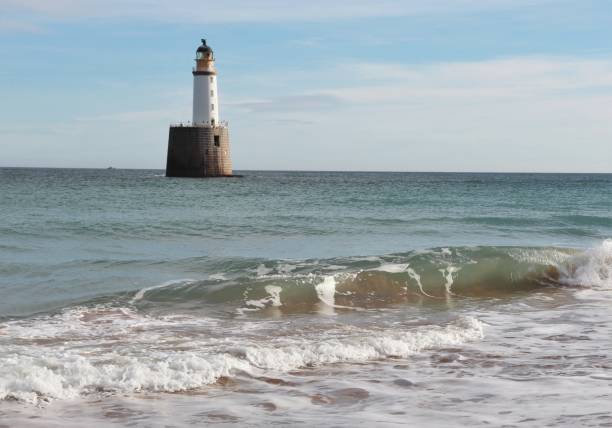 istock Seascape with white lighthouse on stone platform in sea 1130683315
