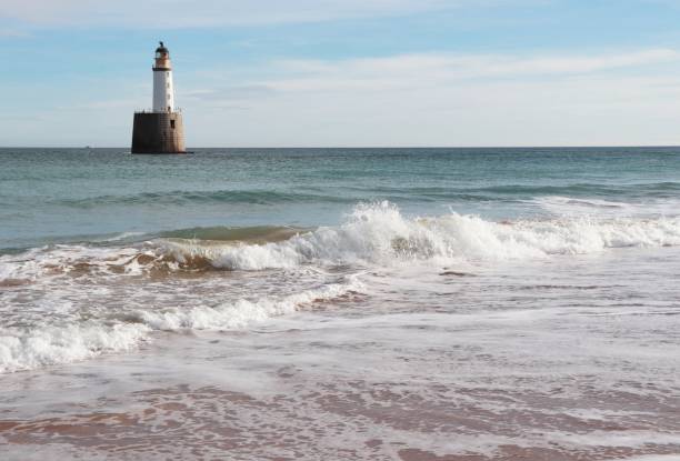 istock Seascape with white lighthouse on stone platform in sea 1130683318