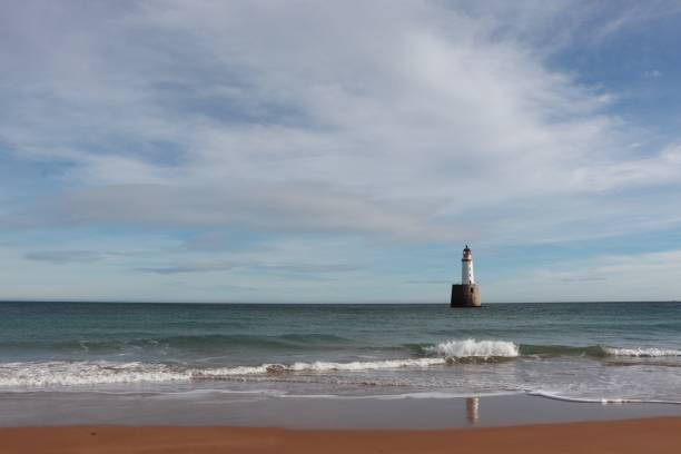 istock Seascape with white lighthouse on stone platform in sea 1130683327