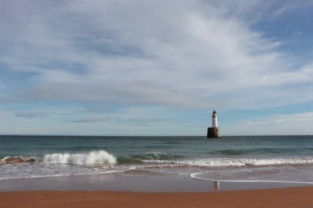 istock Seascape with white lighthouse on stone platform in sea 1130683334