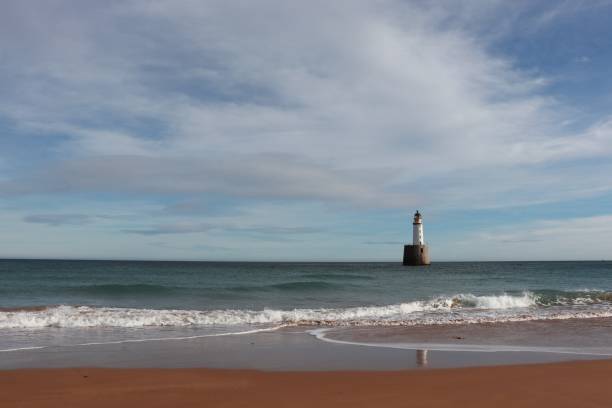 istock Seascape with white lighthouse on stone platform in sea 1130683340