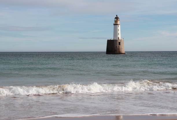 istock Seascape with white lighthouse on stone platform in sea 1130683341