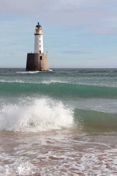 istock Seascape with white lighthouse on stone platform in sea 1130683353