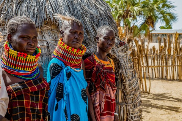 Women of the Turkana tribe, standing outside the ekol, the daytime hut. Two are wearing marriage beads from husband, the chief. The other woman is betrothed to the chief, awaiting him to gather the dowry. Turkana people practice polygamy. Eliye Springs, Lake Turkana, Kenya, Africa, June 15, 2018 kenyan man stock pictures, royalty-free photos & images