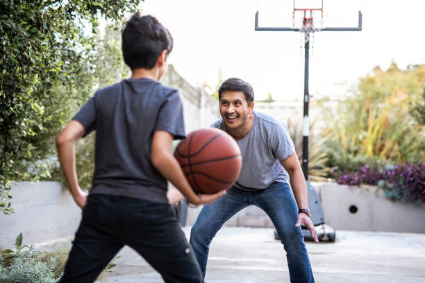 padre e hijo hispanos jugando baloncesto en el patio trasero - bouncing ball family playing fotografías e imágenes de stock