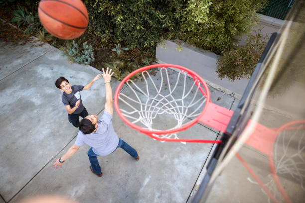 hijo disparando la pelota al aro de baloncesto al aire libre - bouncing ball family playing fotografías e imágenes de stock